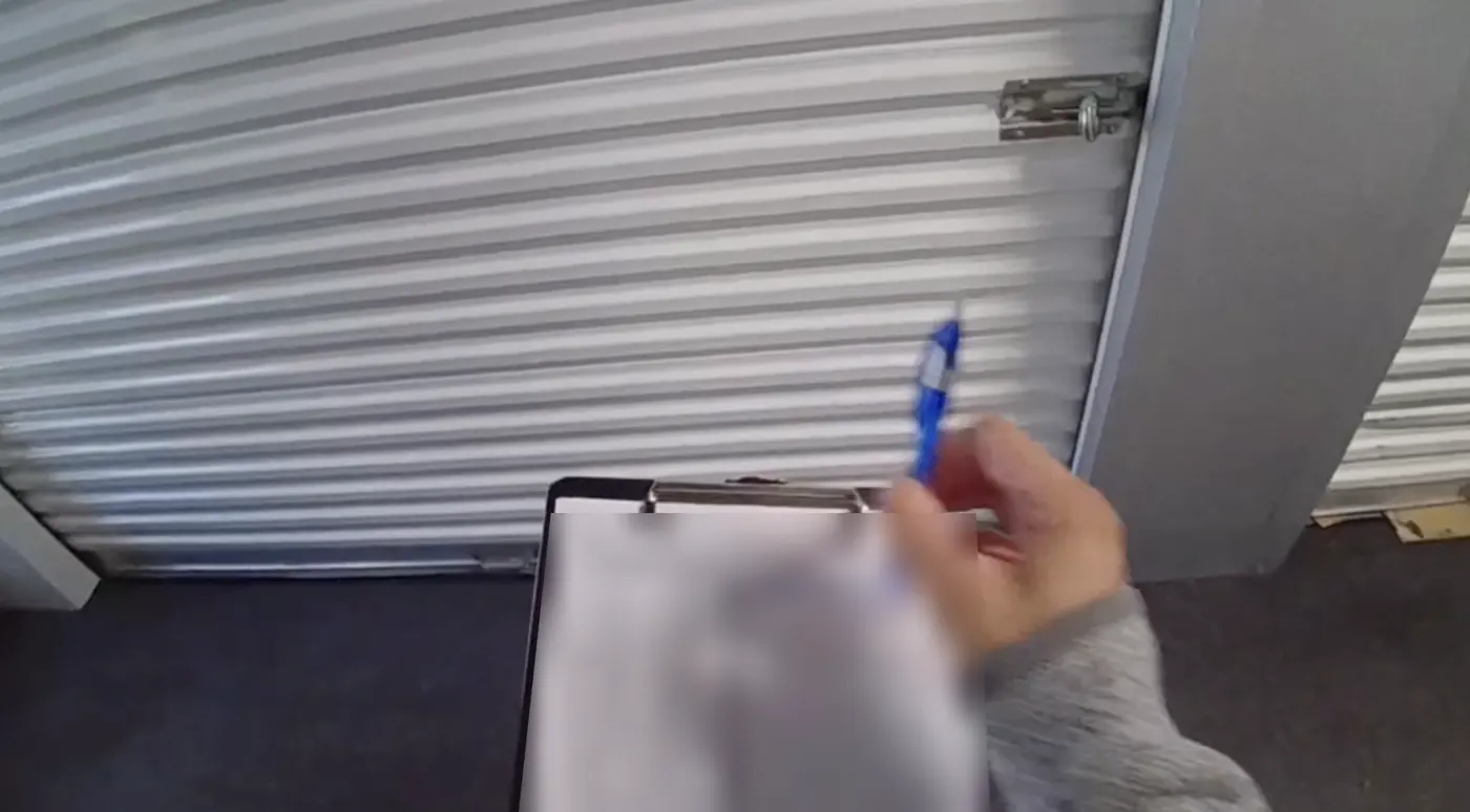 Staff member recording a lock check on a paper clipboard at a storage unit